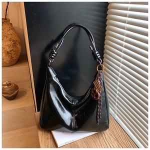 Detail of black wax leather hobo bag with braided knot strap and vintage charms