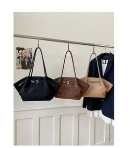 Detailed view of three large suede tote bags in black, brown, and khaki on a hanger