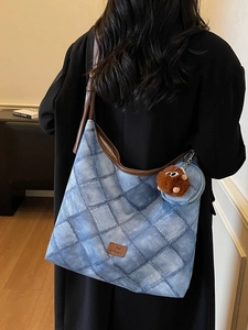 Blue denim patchwork tote bag with brown leather trim and fuzzy monster charm