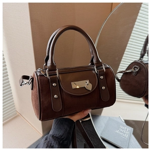 Détail d'un sac seau marron en daim et cuir lisse avec un pendentif en forme de cœur
