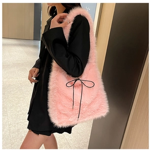Sac à épaule en fausse fourrure rose avec nœud noir porté par un mannequin femme