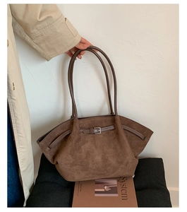 Close-up of brown suede tote bag featuring slim leather straps and metal buckle detail