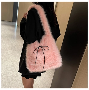Détail du sac fourre-tout rose en fausse fourrure avec un nœud noir sur l'épaule
