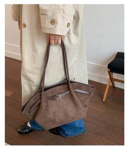 Brown suede tote bag with leather strap and silver buckle detail on a beige trench coat