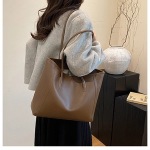 Minimalist dark brown leather tote bag shown on model in a modern home interior setting