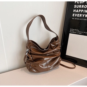 Dettaglio della texture in pelle verniciata marrone scuro e design a pieghe della borsa