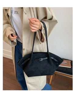 Detail of a black matte vintage tote bag worn over the shoulder with a stylish trench coat