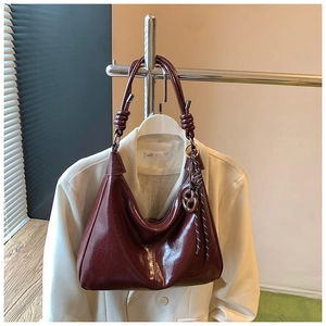 Detail of burgundy wax leather handbag with thick knotted handle and metal ring