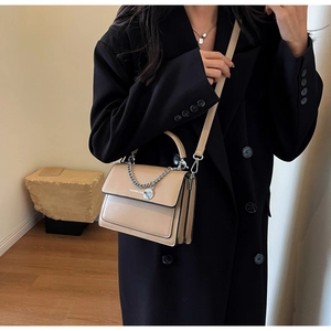 Detail view of khaki minimalist handbag with silver chain and crossbody strap on model