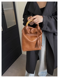 Detalle de bolso cubo marrón retro con asa de madera y adorno de flecos elegante