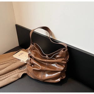 Dettaglio della borsa a spalla in pelle verniciata marrone con eleganti pieghe lucide
