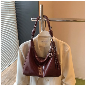 Detail view of burgundy oil wax leather texture and decorative knot on shoulder bag