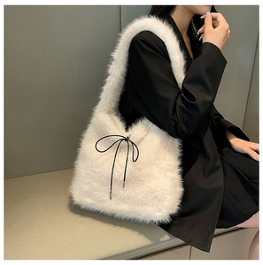 Détail du sac cabas en fausse fourrure blanche avec nœud noir et texture peluche