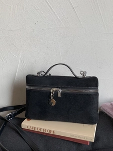 Minimalist black suede top-handle crossbody box bag with silver hardware on books