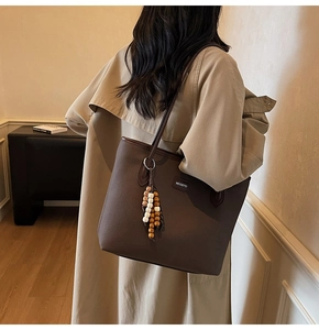 Detail der dunkelbraunen Leder-Shopper mit Ethno-Holzperlenquaste und Logo-Aufnäher