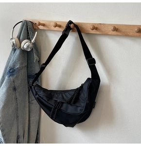 Detail einer schwarzen Nylon-Halbmondtasche mit gewebtem Reißverschlusszug am Holzhaken
