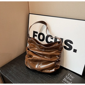 Dettaglio di una borsa hobo in pelle verniciata a pieghe marrone scuro lucida elegante