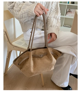 Detailed texture of camel suede tote bag featuring decorative belt buckle and long straps