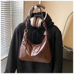 Macro shot of dark brown polished oil wax leather hobo bag with braided ring charm