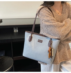 Detail der graublauen Shopper-Tasche mit braunem Lederbesatz und Retro-Holzperlen-Quaste