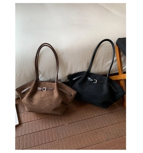 Detail view of large matte suede tote bags in brown and black with silver buckle