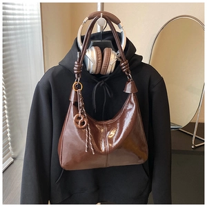 Detail of dark brown leather hobo bag with unique knot strap and round charm decor