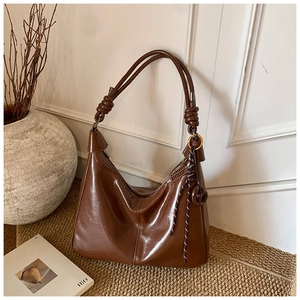 Close-up of dark brown hobo bag featuring handcrafted leather knot and golden hardware