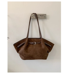 Detail of dark brown suede tote bag with leather buckle strap and fine stitching
