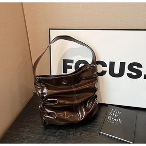 Dettaglio della trama in pelle verniciata plissettata marrone scuro di una borsa vintage
