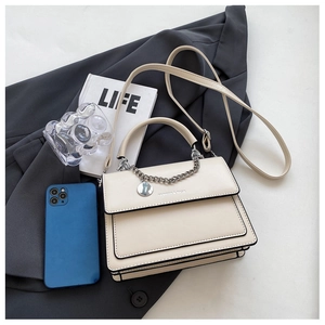 Detail of cream vintage flap bag with black edge piping and silver metal chain accessory