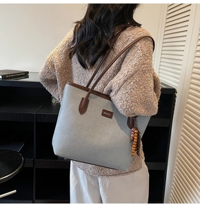 Detail der grauen Stoff-Tasche mit braunem Leder und ethnischem Holzperlen-Anhänger
