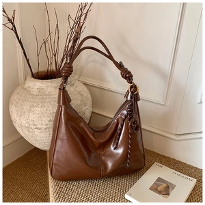 Detail of vintage dark brown faux leather hobo bag with knot strap and metallic buckle