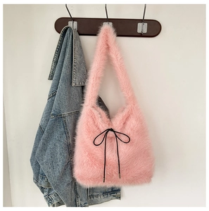 Gros plan du sac cabas en fausse fourrure rose avec un nœud noir sur un crochet