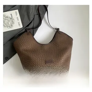 Dettaglio della trama intrecciata marrone e del logo del marchio sulla borsa in pelle