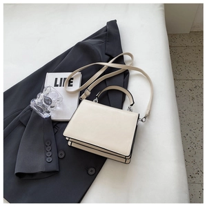 Close-up of cream square handbag with accordion pleats and black edge paint detail