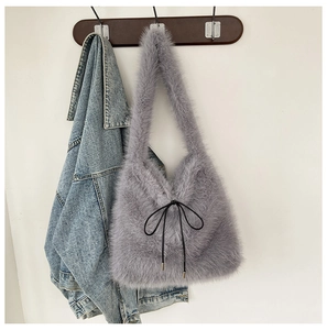 Détail du sac à épaule gris en fausse fourrure avec nœud noir sur un crochet en bois