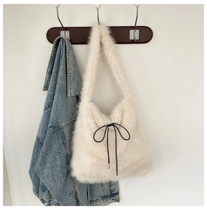 Détail du sac fourre-tout en fausse fourrure crème avec nœud noir sur denim
