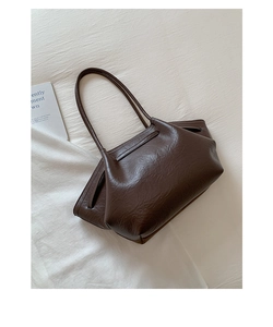 Detail of vintage dark brown tote bag with pleated leather texture on white fabric