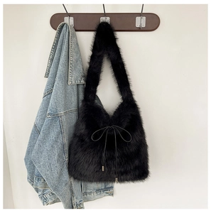 Détail d'un sac à bandoulière en fausse fourrure noire avec nœud sur veste en jean