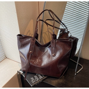 Detail of dark brown patent leather tote with crackle texture and metal rivet accents