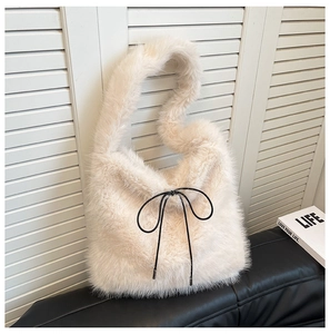 Détail d'un sac fourre-tout en fausse fourrure crème avec un nœud en ruban noir fin