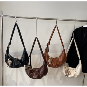 Detail view of four colorful hobo bags hanging on a rack with plush pendants