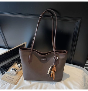 Detailaufnahme der braunen Canvas-Tasche mit Lederbesatz und Perlen-Anhänger-Detail