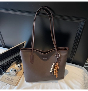 Detailansicht braune Shopper Tasche mit Ethno-Perlenanhänger und Markenlogo
