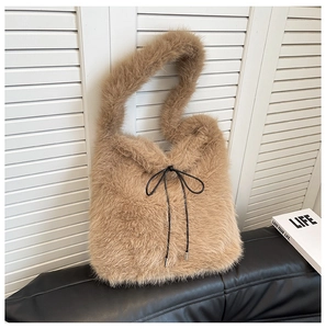 Détail d'un sac cabas en peluche montrant la texture douce et le cordon en ruban noir