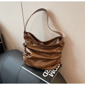 Dettaglio di una borsa hobo marrone lucida plissettata in un elegante set vintage