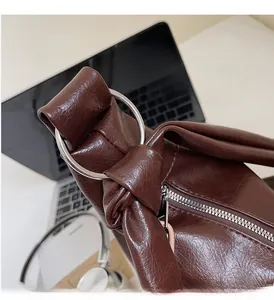 Detail of dark brown leather bag with silver metal ring and knotted strap design