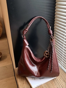 Vintage burgundy leather hobo bag with knotted shoulder strap and glossy texture