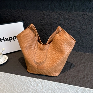 Dettaglio della trama intrecciata marrone caramello e logo impresso sulla borsa tote