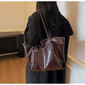 Detail of glossy vintage tote bag with long straps and gold rivet accents